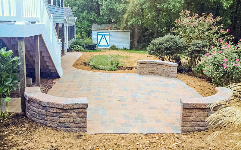 Image of a patio with three seat walls in a rounded rectagle format, with a walkway.